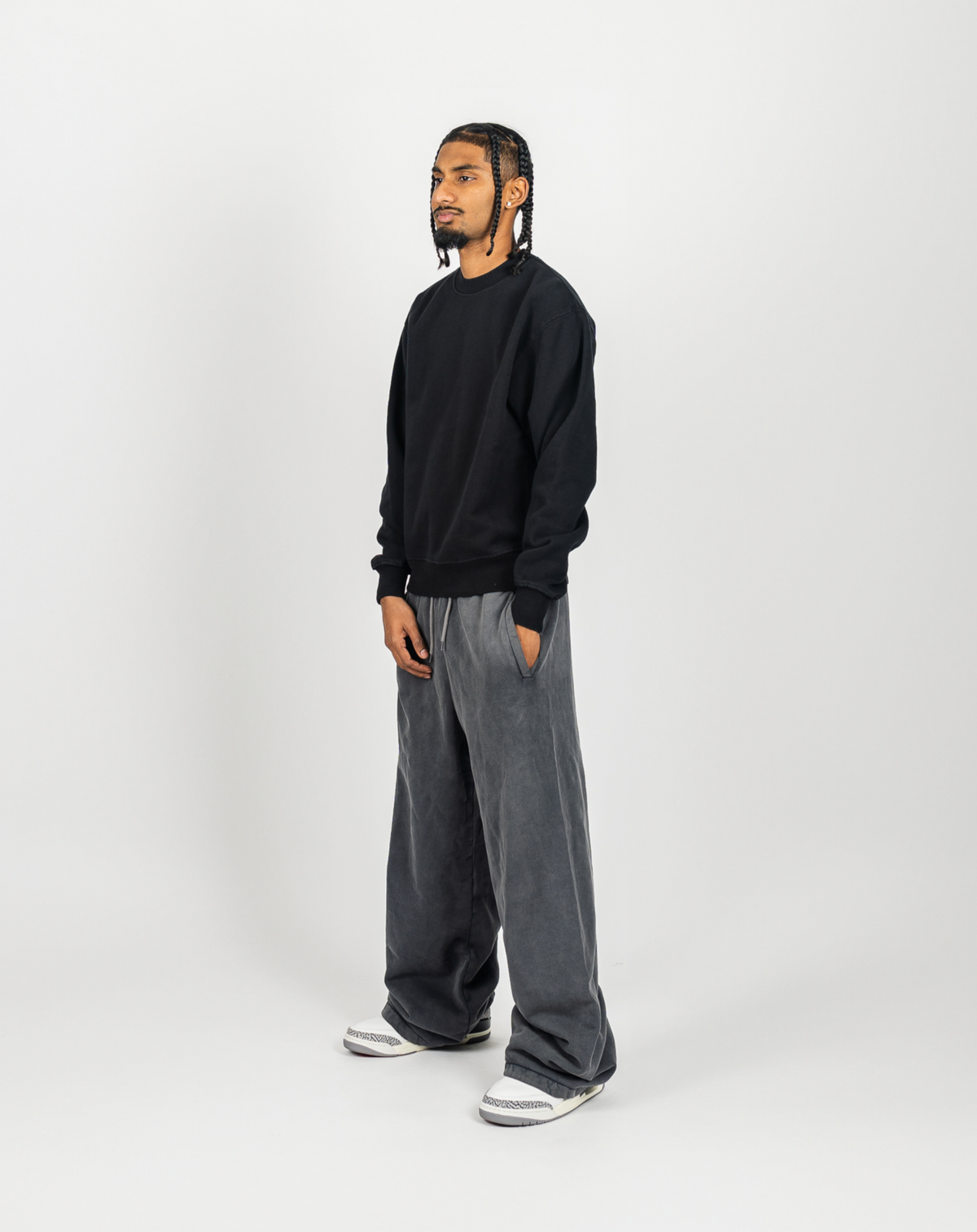 Person wearing a black sweater and gray pants on a white background